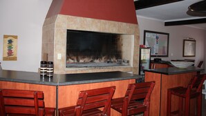 Una cocina con chimenea integrada, taburetes de madera y salpicadero de azulejos.