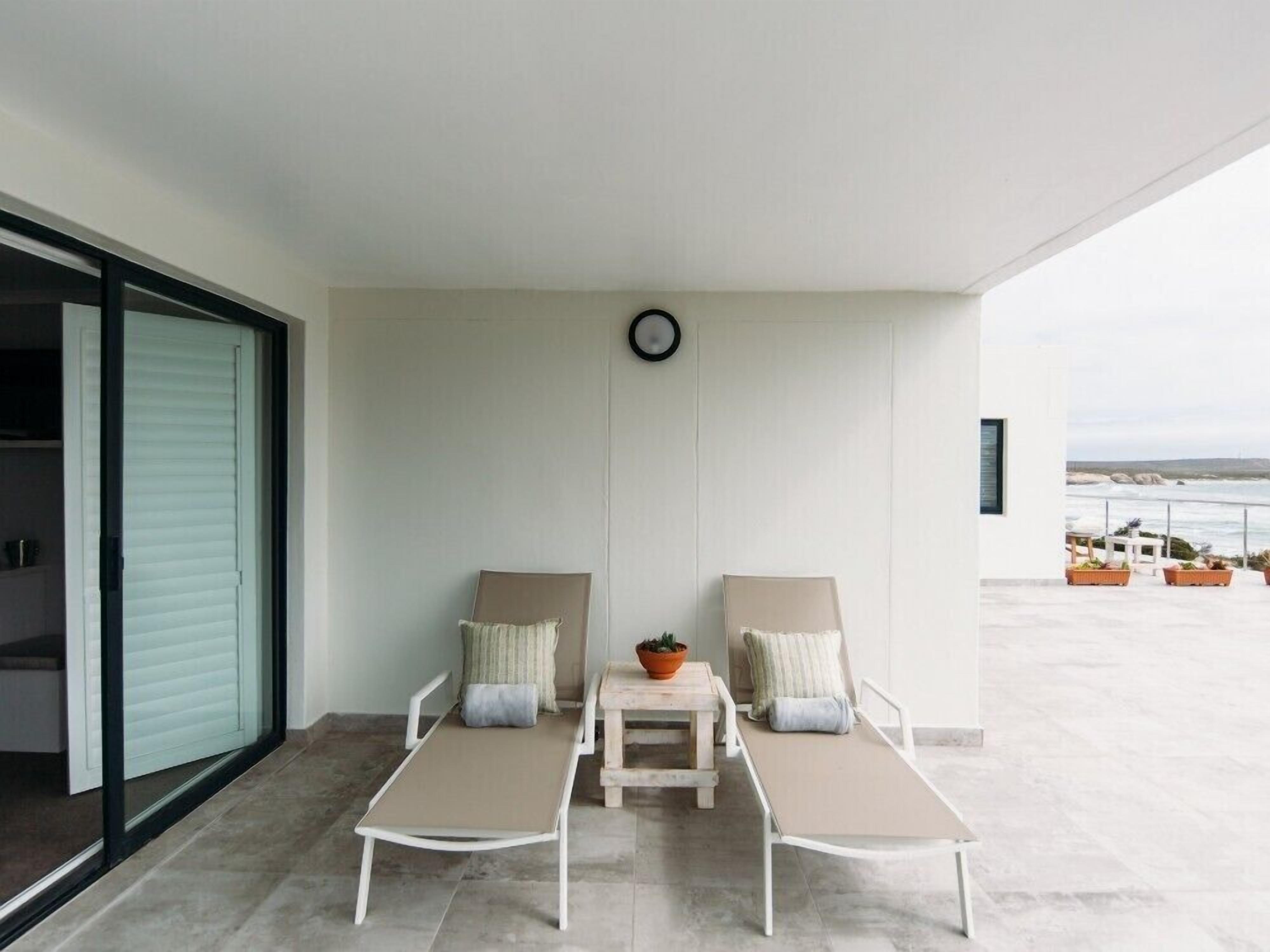 Un balcone con due poltrone, un tavolino con una pianta in vaso, e vista sul mare.