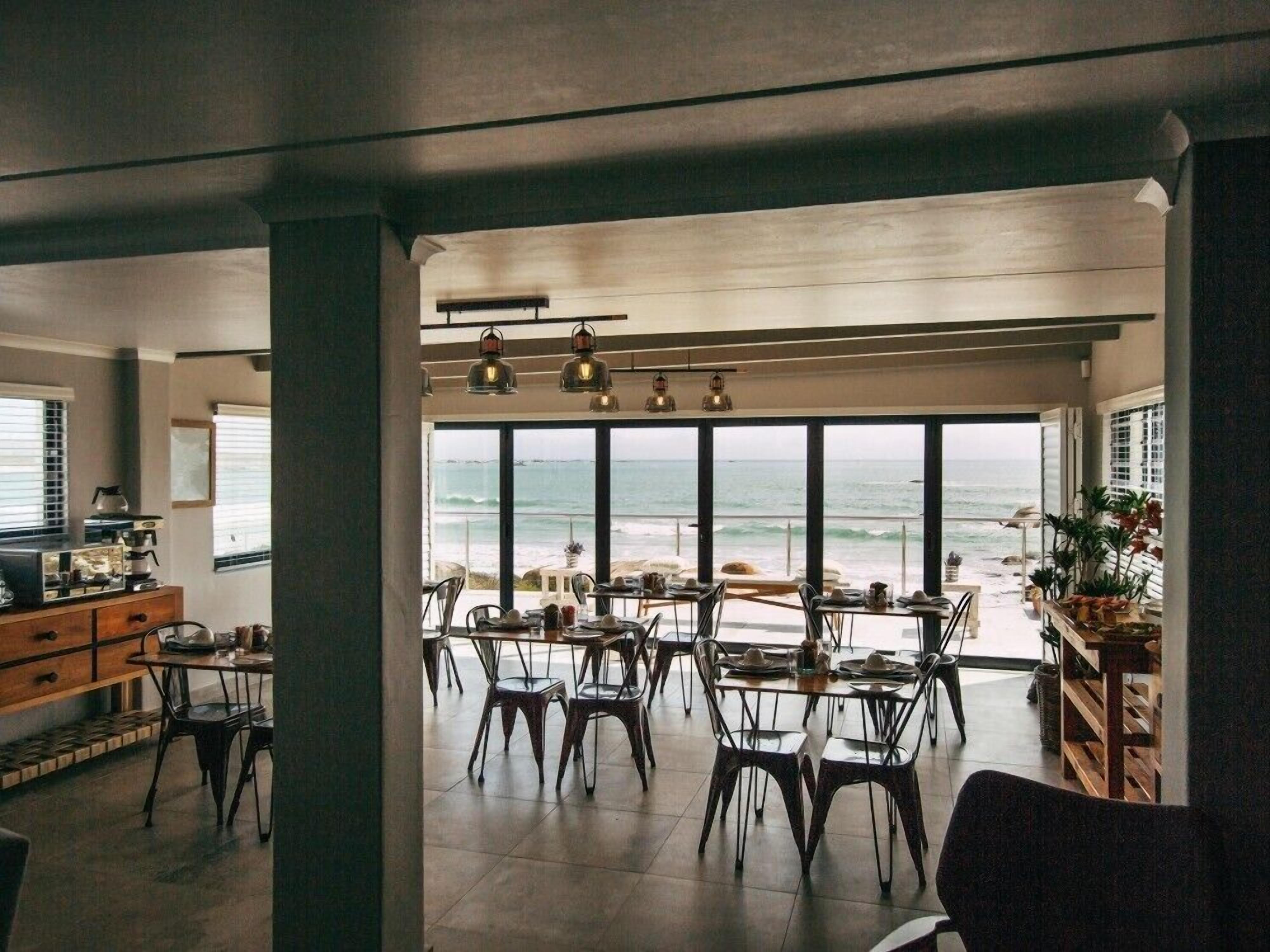 A spacious dining area with high ceilings and large windows overlooking the beach.