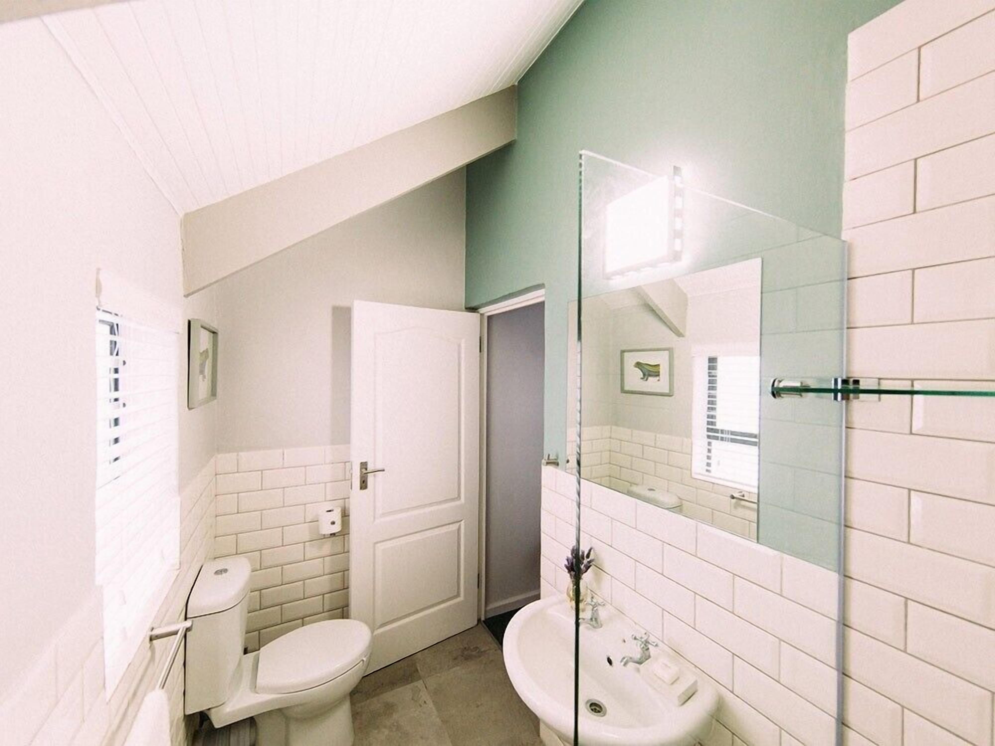 A bathroom with a toilet, sink, and shower area.