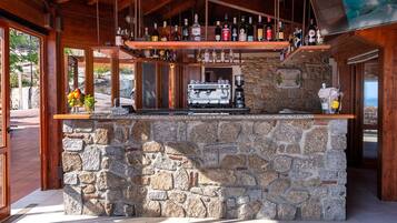 A stone bar with a coffee machine and various bottles.