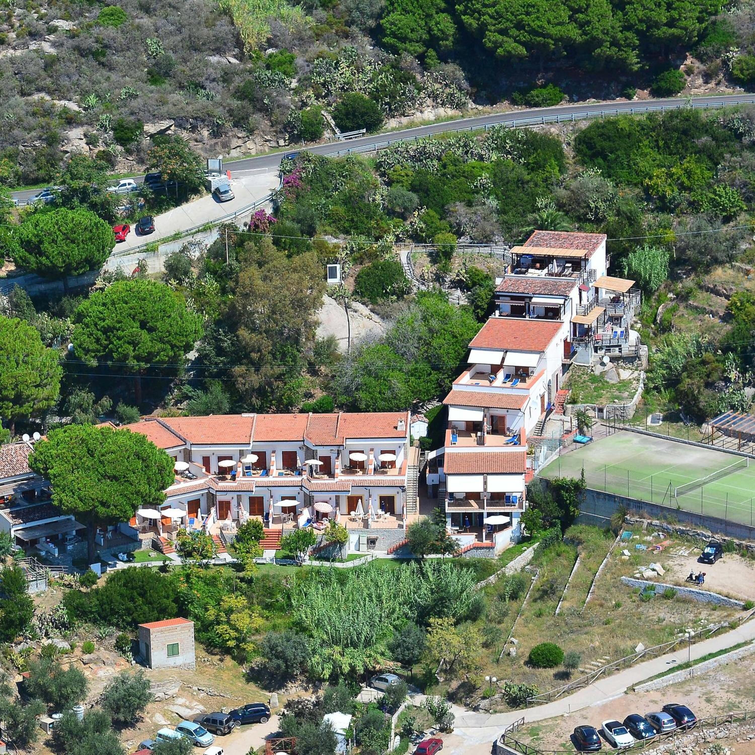 Zona residencial con varias edificaciones de dos pisos, una cancha de tenis y un estacionamiento.