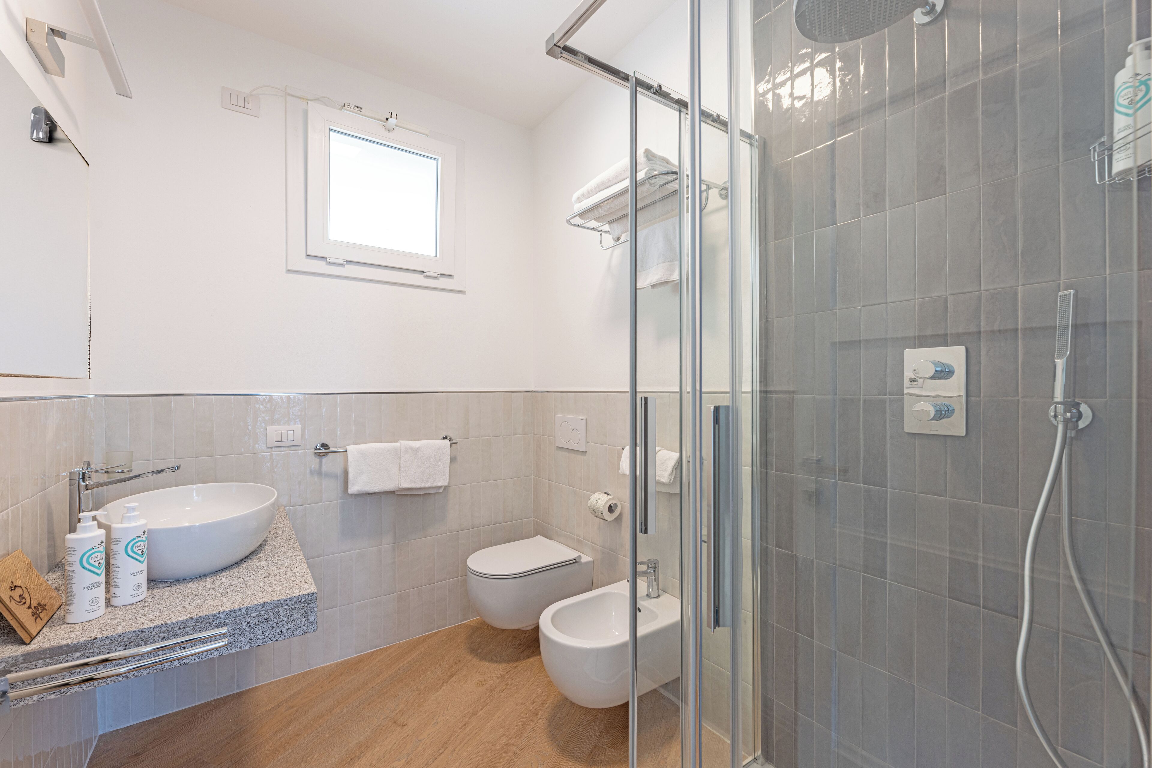 Un baño moderno con una bañera independiente, ducha con mampara de vidrio, inodoro y lavamanos.