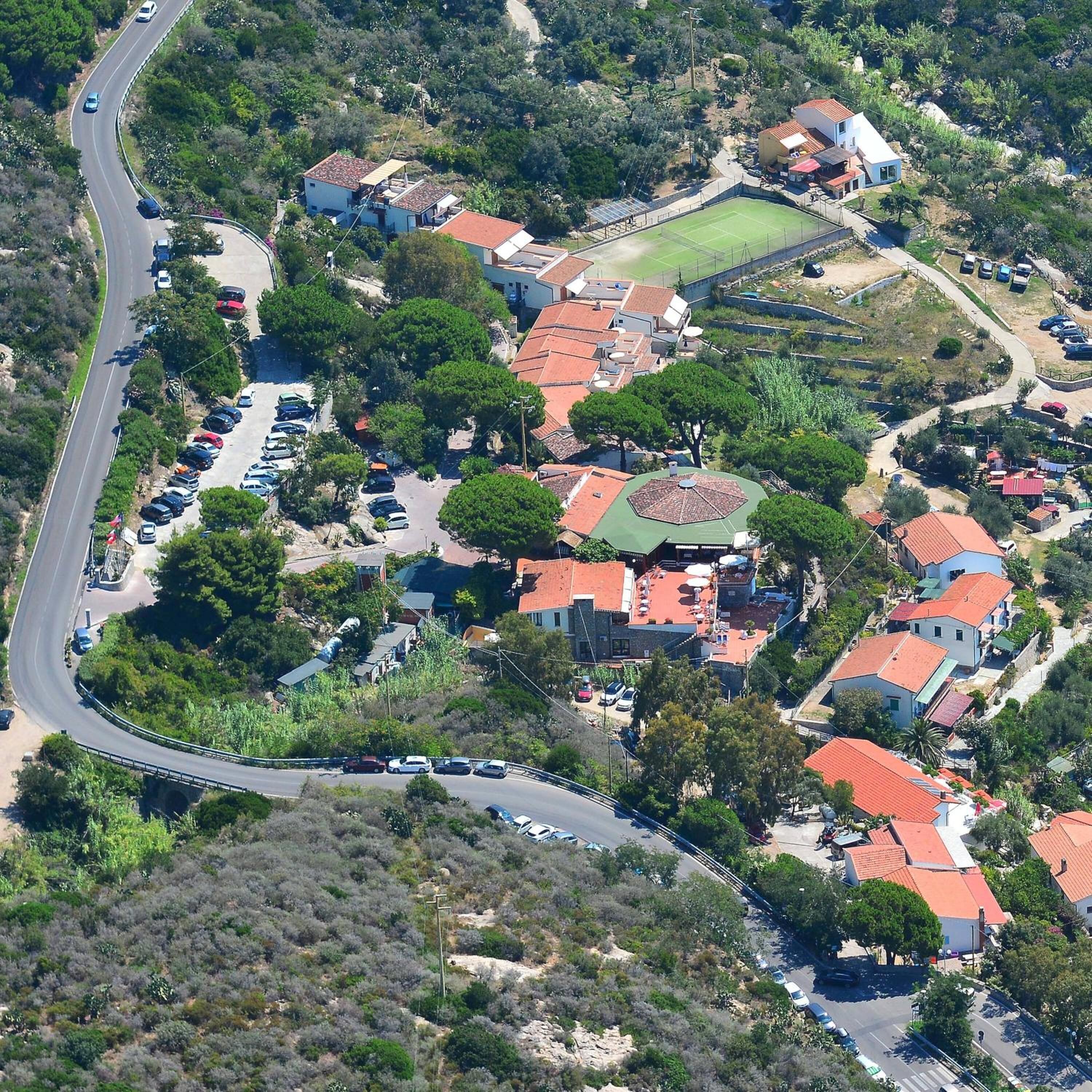 An aerial view of a residential area with houses, a curved road, and a sports field.