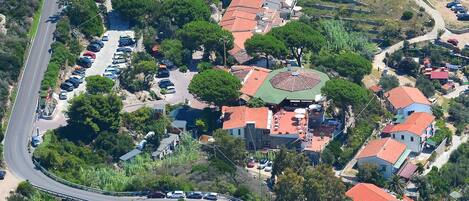 An aerial view of a residential area with houses, a curved road, and a sports field.