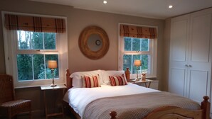 A bedroom with a wooden bed, two bedside tables with lamps, a chair, and a wardrobe. - Bournes Farmhouse (Henley-on-Thames)