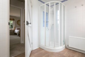 A modern bathroom with a glass shower enclosure, white tiled walls, and a wooden floor. - Bournes Farmhouse (Henley-on-Thames)