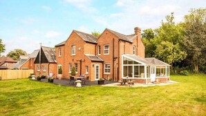 A large brick house with a conservatory and a well-maintained lawn. - Bournes Farmhouse (Henley-on-Thames)
