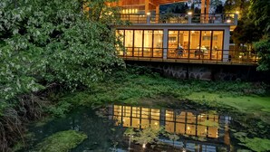 A modern house with a wooden deck and large windows overlooking a pond. - Purespace (Zhangjiajie)