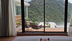 A bedroom with a large window overlooking a lush green hillside and a body of water. - Purespace (Zhangjiajie)