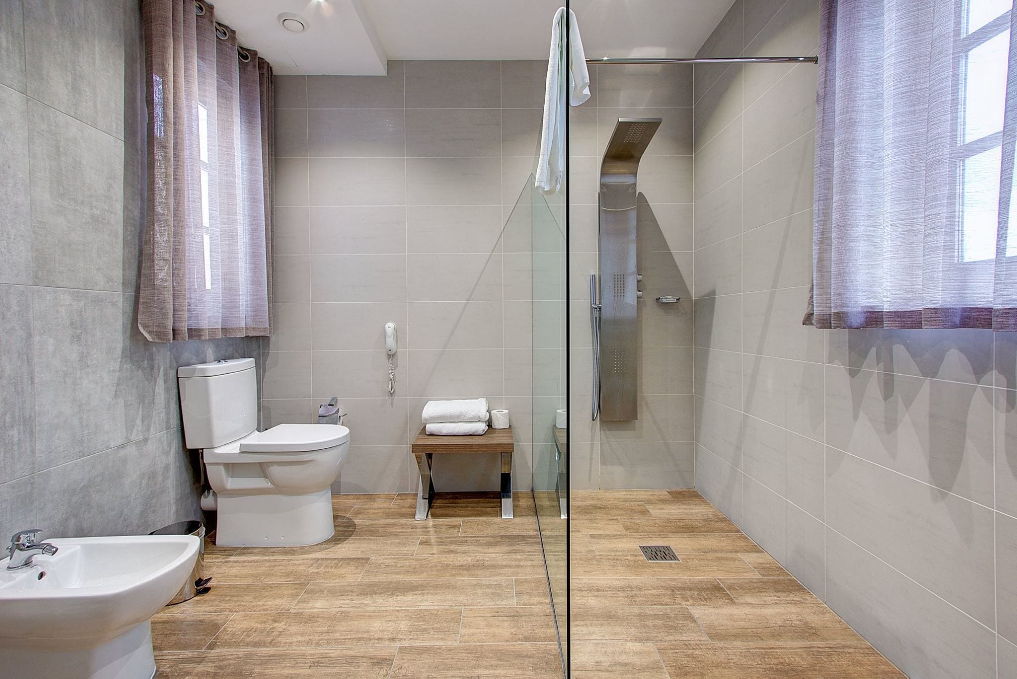 Un baño moderno con ducha de vidrio, inodoro, bidé y lavamanos.