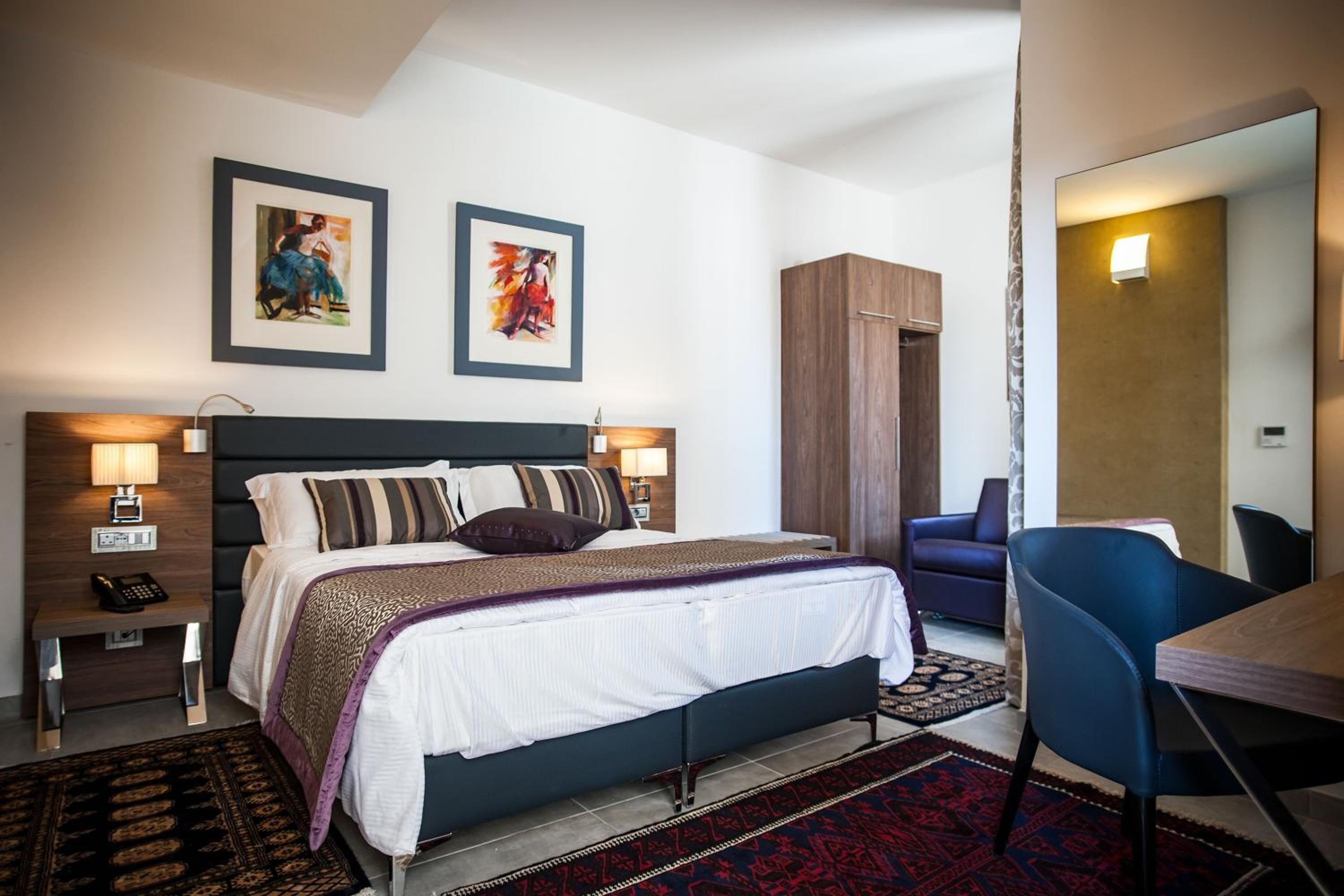 Una habitación de hotel moderna con una cama grande, mesitas de noche, un escritorio y una silla.