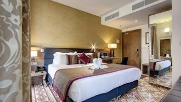 A hotel room with a large bed, bedside tables, a mirror, and a patterned floor.