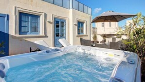 A hot tub with a clear view of the surrounding area, including a building with blue shutters and a large umbrella. - Palazzo Paolina Boutique Hotel (Valletta)