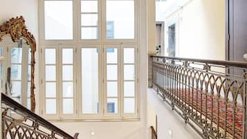 A staircase with a red carpet, white walls, and a wooden ceiling.