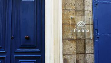 Una puerta azul con un pomo redondo y una pared de piedra con un cartel que indica 'Palazzo Paolina Boutique Hotel'.