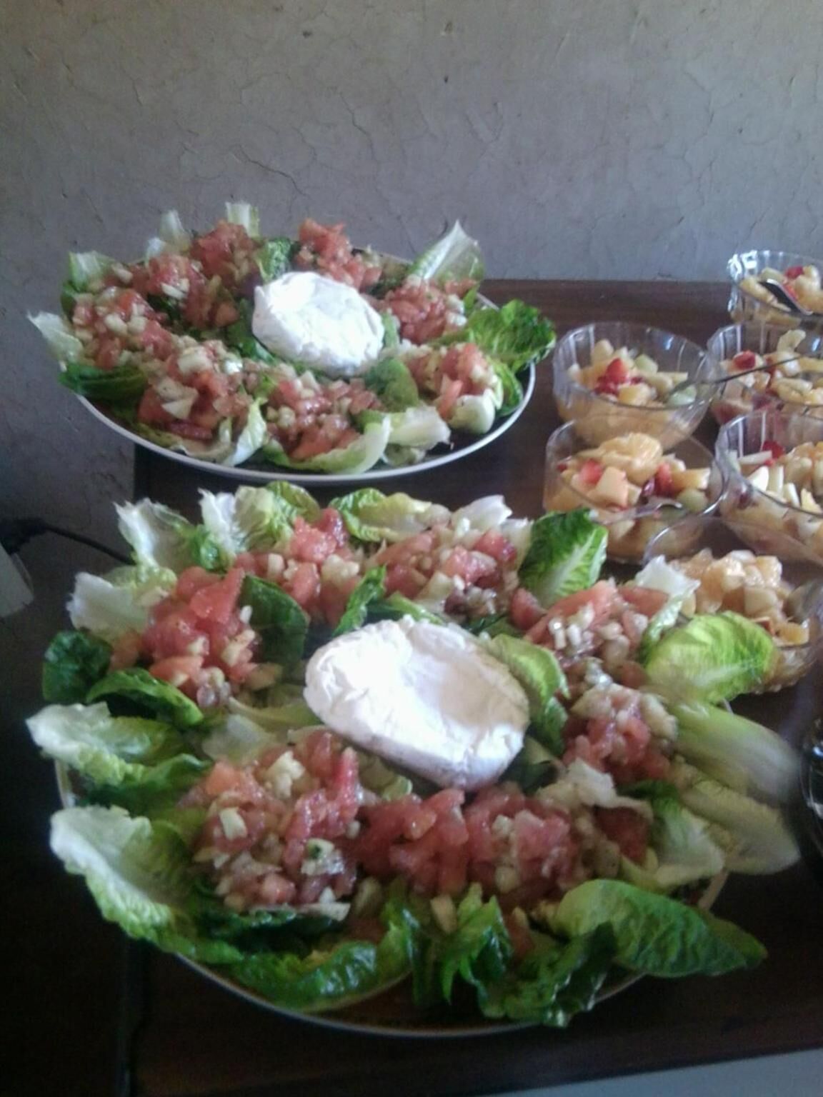 A table with multiple plates of salad, including lettuce, tomatoes, and a white creamy topping.