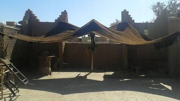 A courtyard with a large tent-like structure, a wooden ladder, and a brick wall.