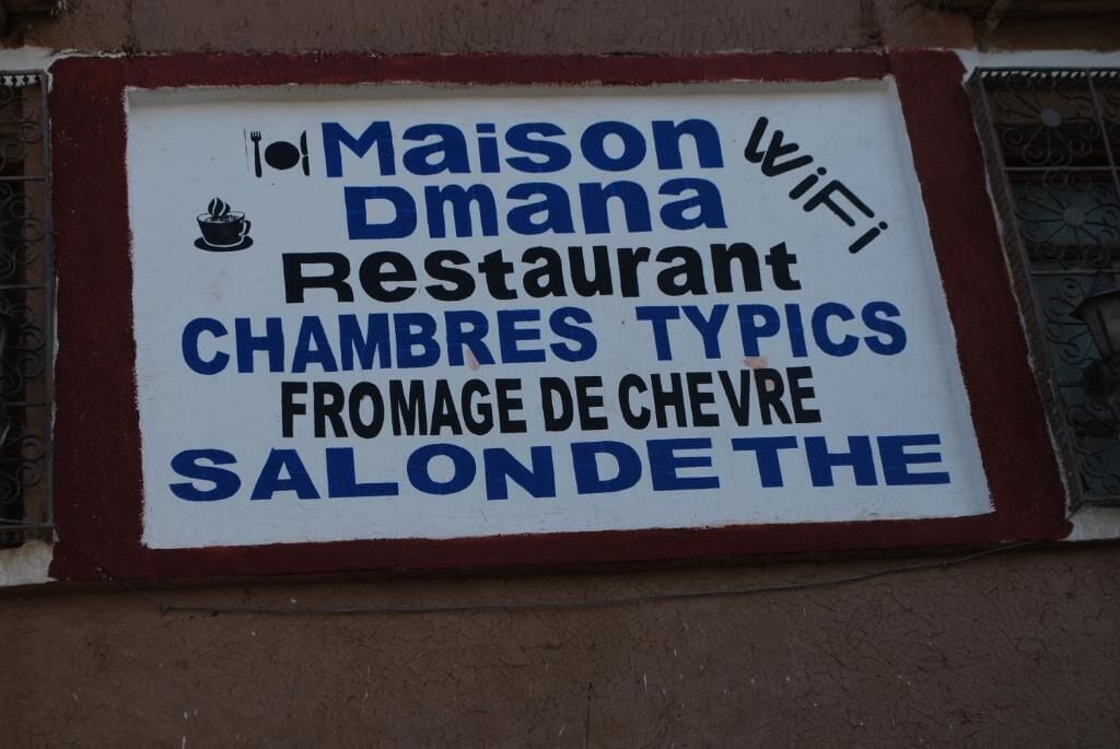 Señal para el Restaurante Maison Dmana, que indica que ofrece cocina francesa tradicional y servicio de WiFi.