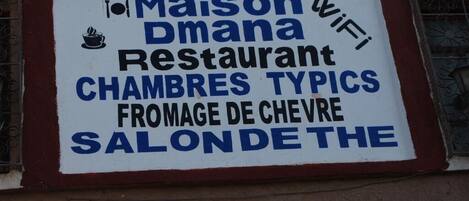 Señal para el Restaurante Maison Dmana, que indica que ofrece cocina francesa tradicional y servicio de WiFi.