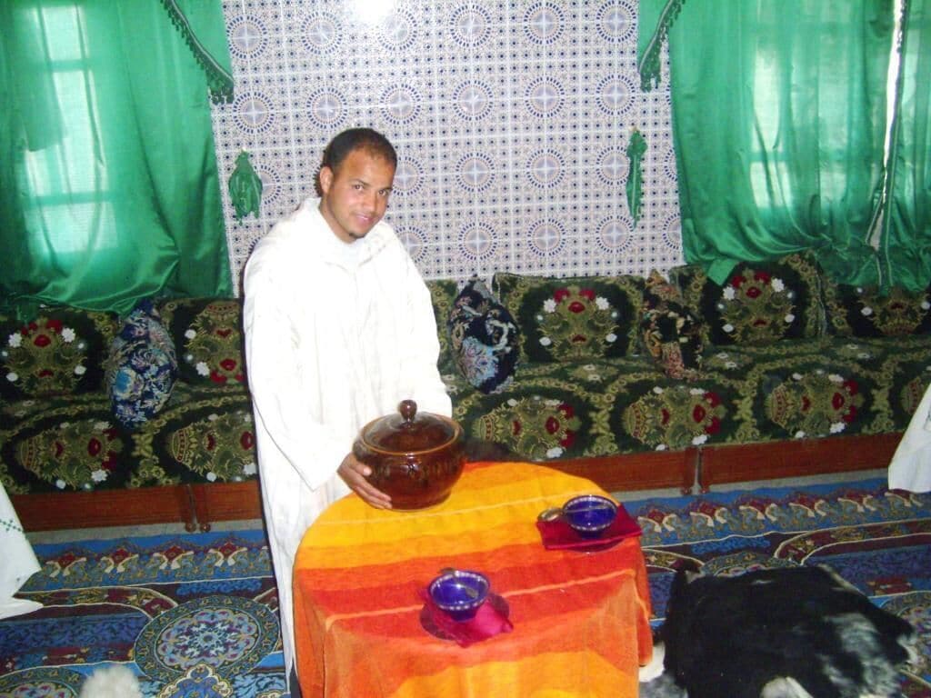 A person standing in a room with patterned carpet and a sofa with floral upholstery.