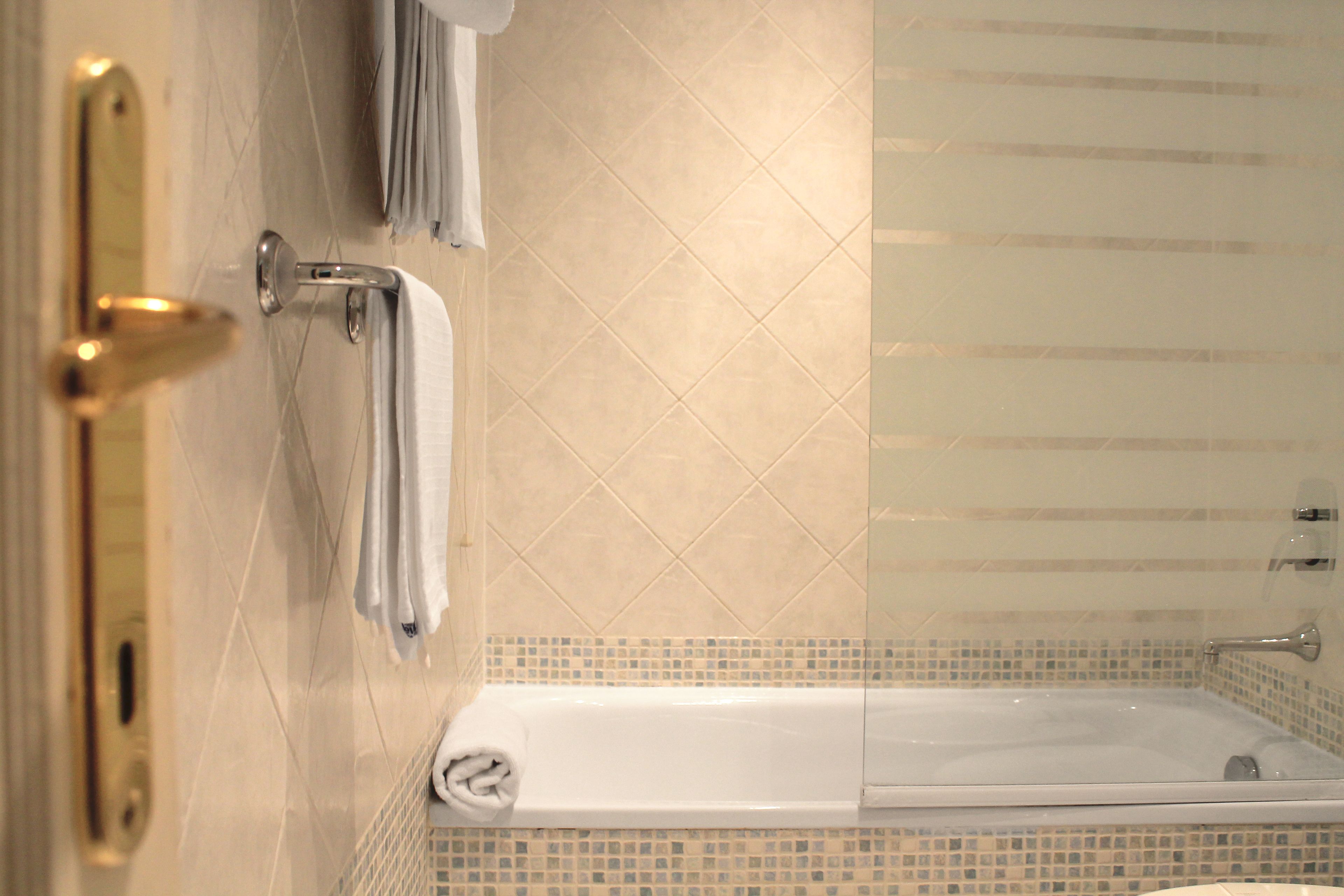 Un baño con bañera, zona de ducha y un perchero para toallas.