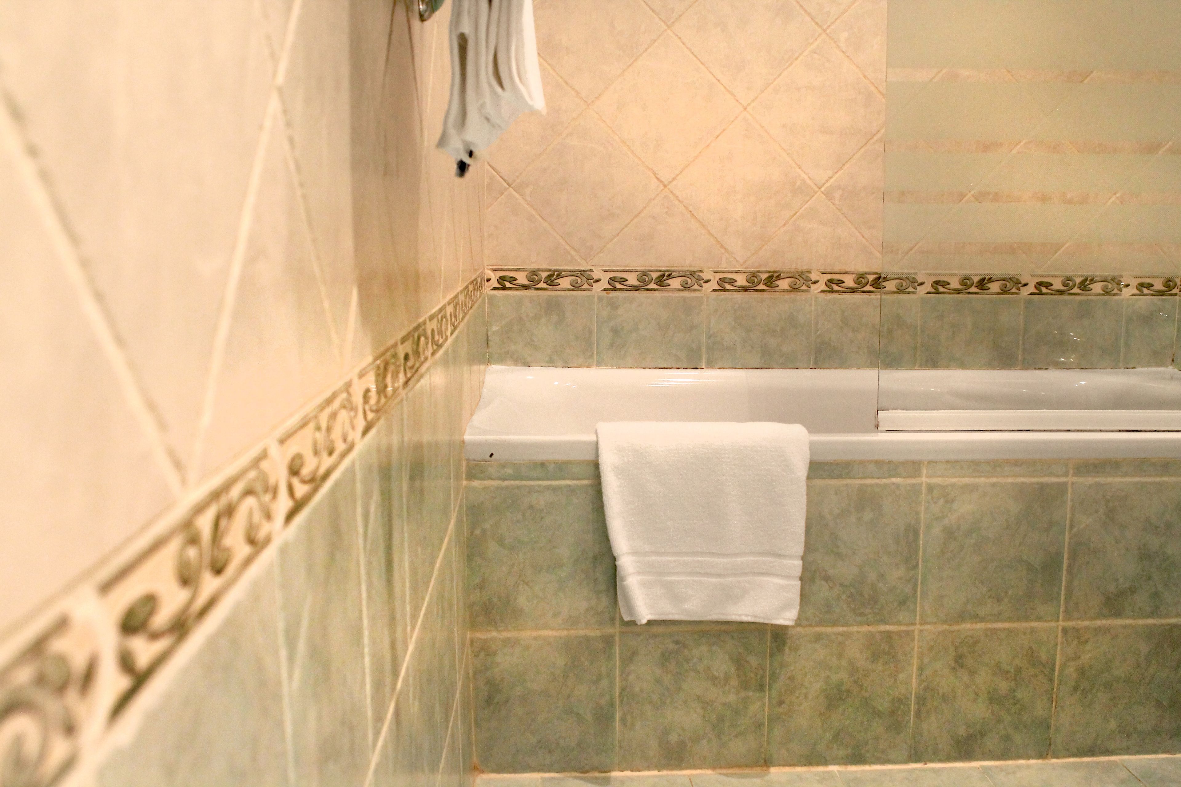 A bathroom with a bathtub, a towel hanging on the wall, and decorative tiles.