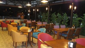 An indoor dining area with wooden tables and chairs, some with cushions. - Cinarpark Hotel (Korfez)