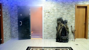 A modern interior with a stone wall, a wooden door, and a decorative tree sculpture. - Cinarpark Hotel (Korfez)