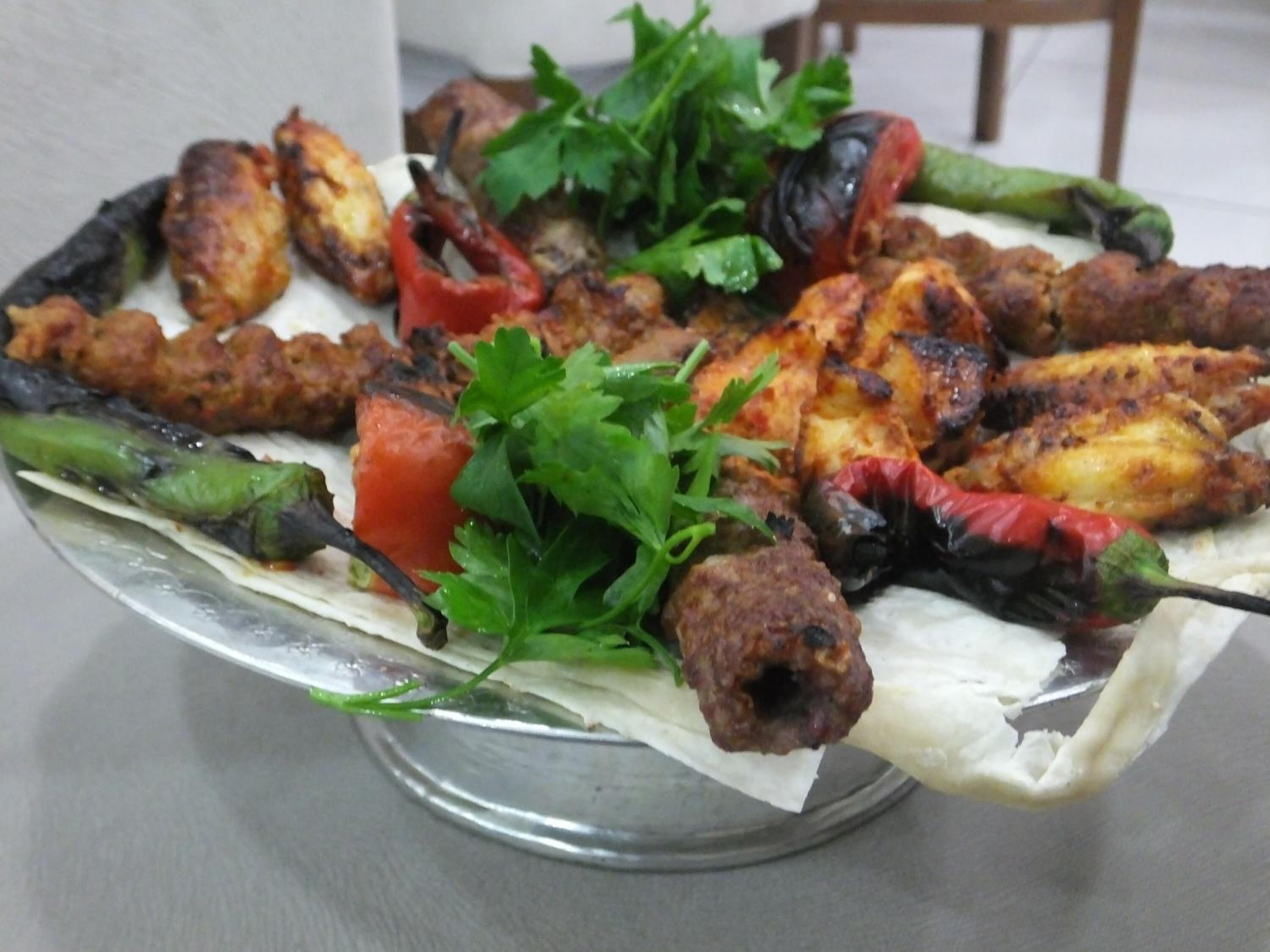 Un plato de kebabs a la parrilla con verduras y perejil.