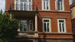Un edificio in mattoni di due piani con un balcone, un ingresso carrabile e un divieto di parcheggio.