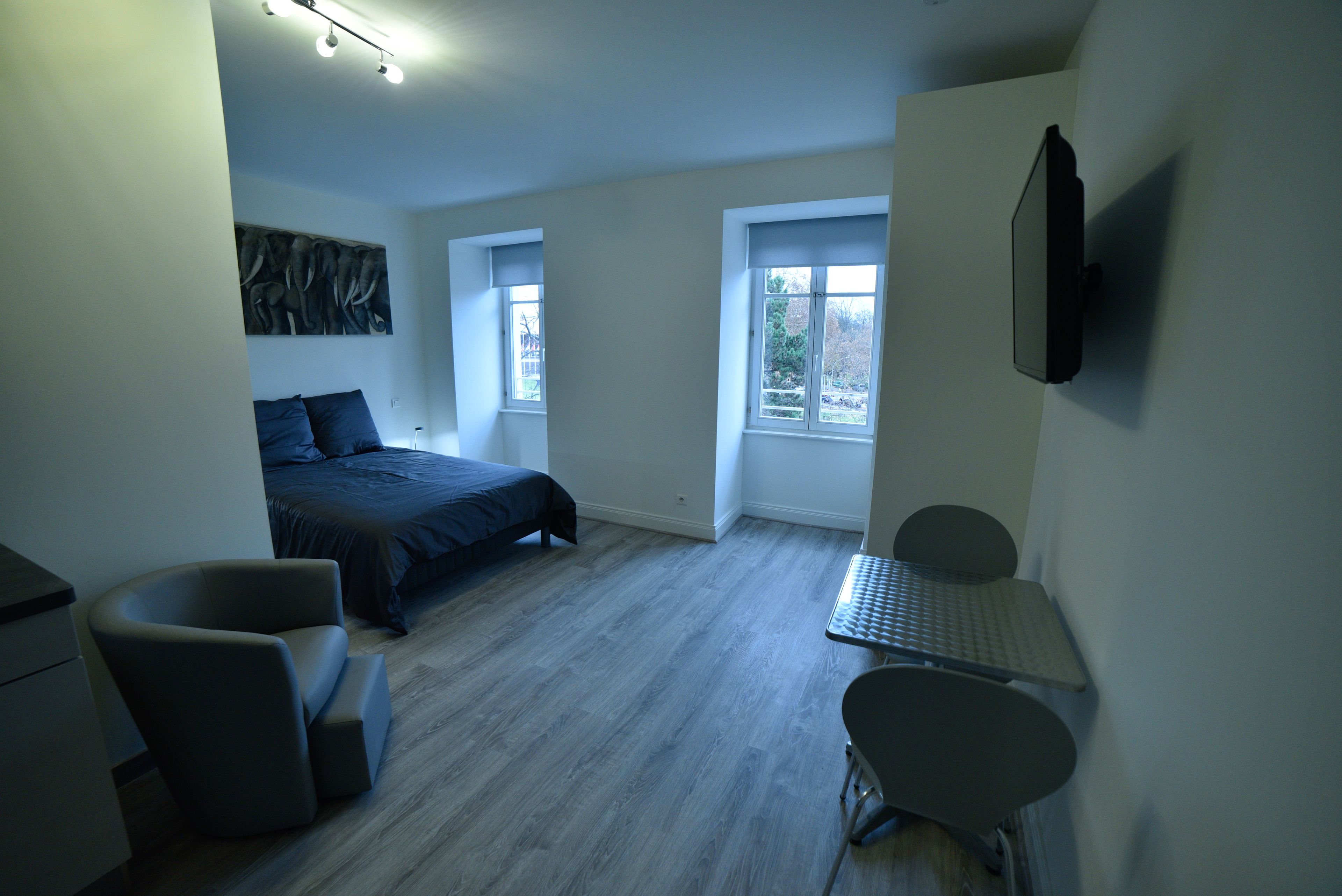 Un dormitorio moderno con cama, escritorio, silla y ventana.