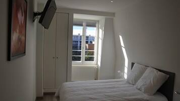 A bedroom with a bed, a wardrobe, and a window.