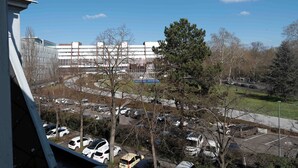 Un parcheggio con diverse auto, un edificio sullo sfondo con molte finestre e un cielo azzurro intenso.