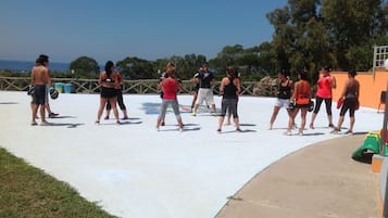A group of people exercising on a concrete surface with a railing and trees in the background.