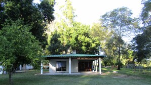A small, single-story house with a green roof, surrounded by trees and grass. - Finca Mombiri (Esquina)