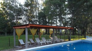 A pool area with a covered seating area and lounge chairs. - Finca Mombiri (Esquina)