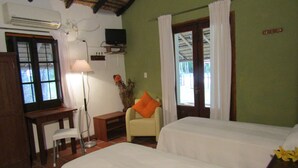 A room with two beds, a desk with a chair, a TV, and a window with curtains. - Finca Mombiri (Esquina)