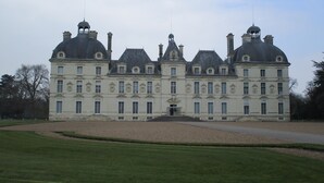 Un grand bâtiment historique à l’architecture symétrique, doté de nombreuses cheminées et d’une entrée centrale.