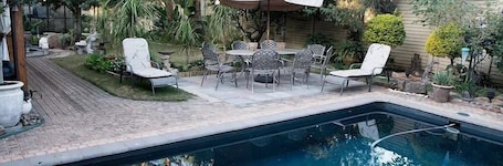 Una piscina al aire libre, sombrillas, sillones reclinables de piscina
