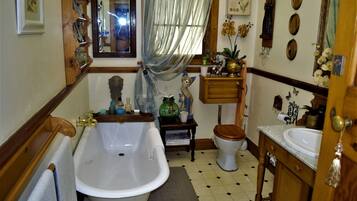 Un baño con bañera, inodoro, lavamanos y tocador de madera.