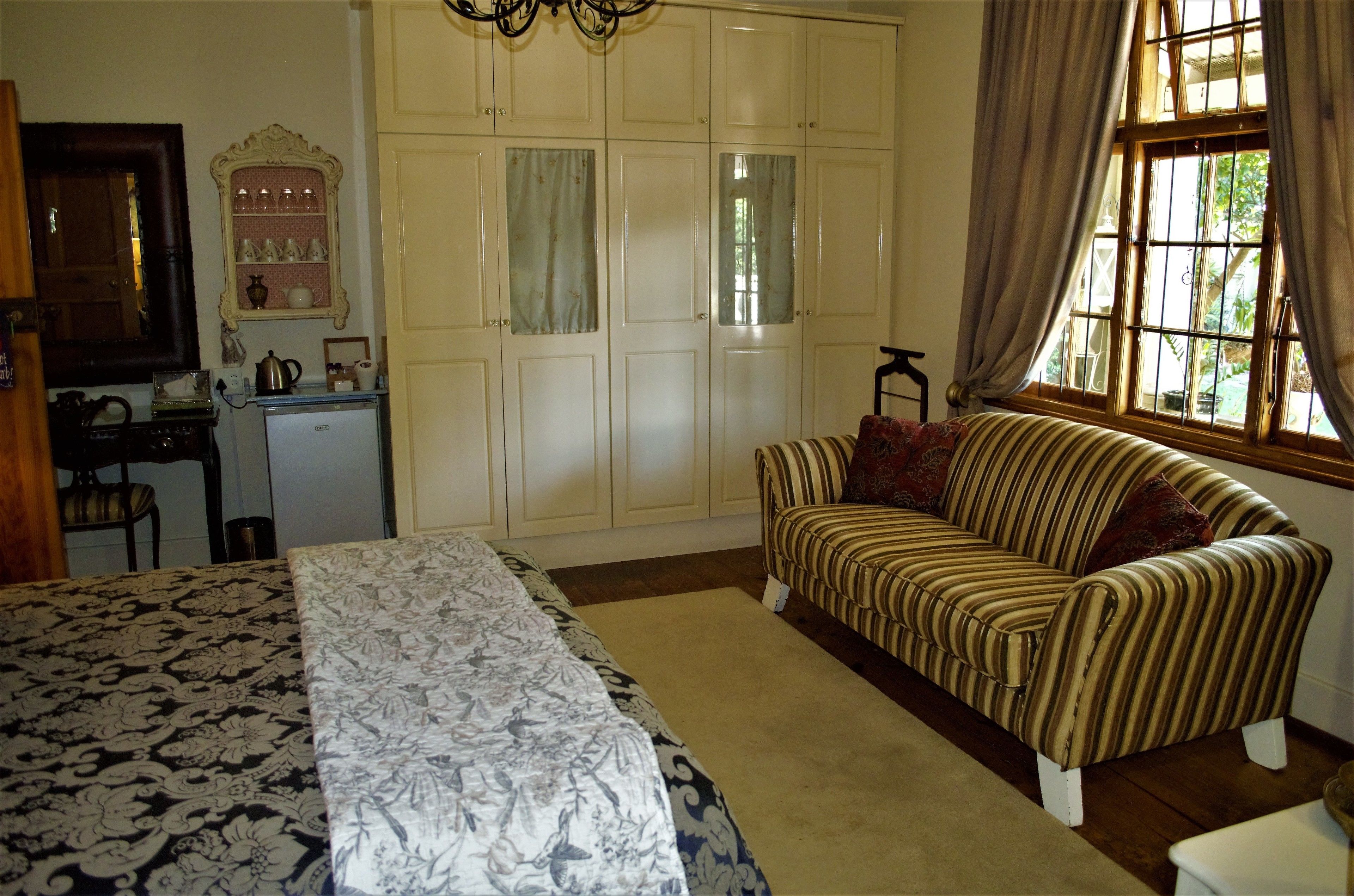 A bedroom with a bed, a sofa, a desk, and a wardrobe.