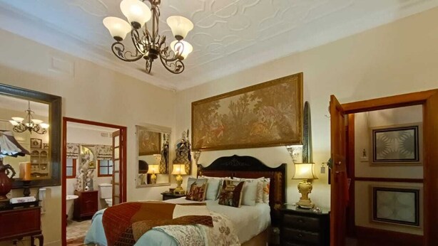 A spacious bedroom with a large bed, a chandelier, and a painting above the bed. - 79 On Ridge BNB (Pietermaritzburg)