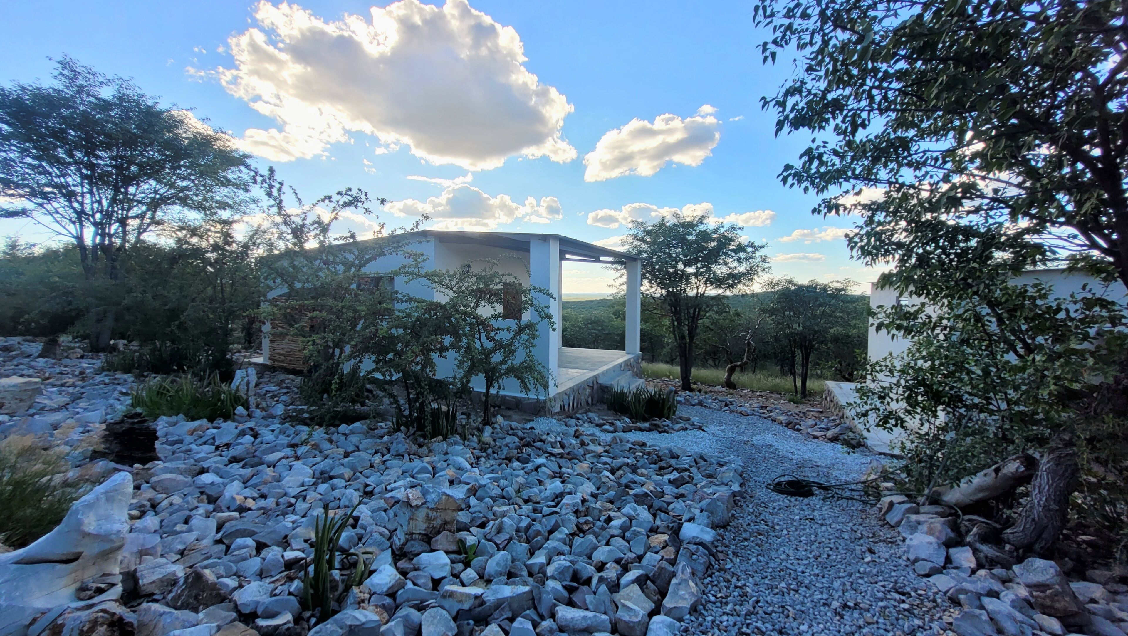 Une structure extérieure moderne, accessible par un chemin de pierre, entourée d’arbres et s’ouvrant sur un ciel dégagé.