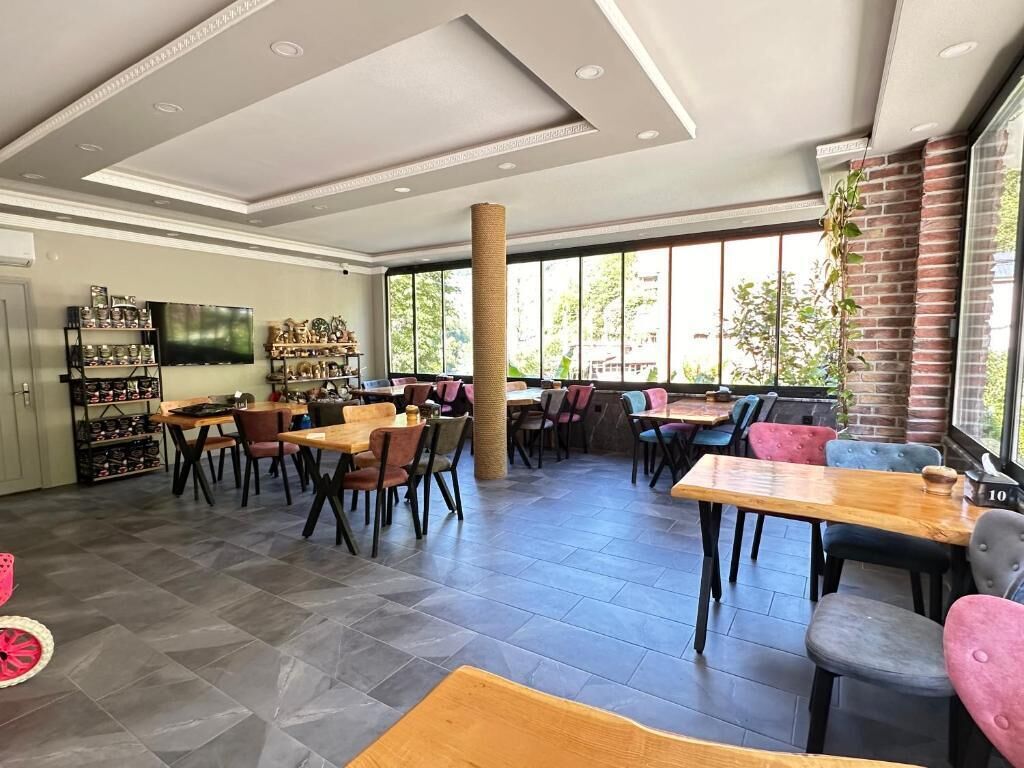 Un espacio interior amplio con varias mesas y sillas, un pilar grande y un muro de ladrillo.