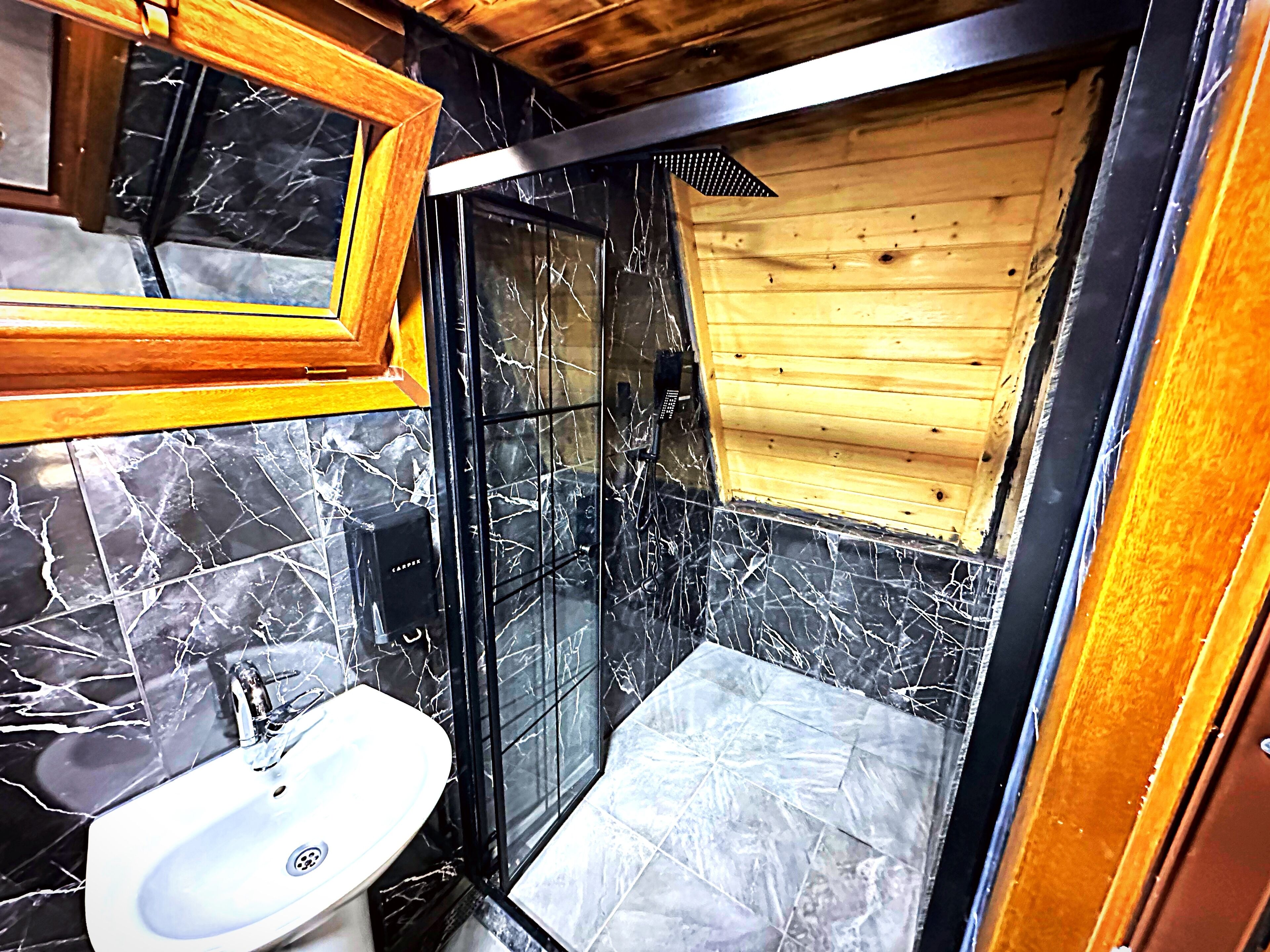 A bathroom with a sink, a shower, and a wooden wall.