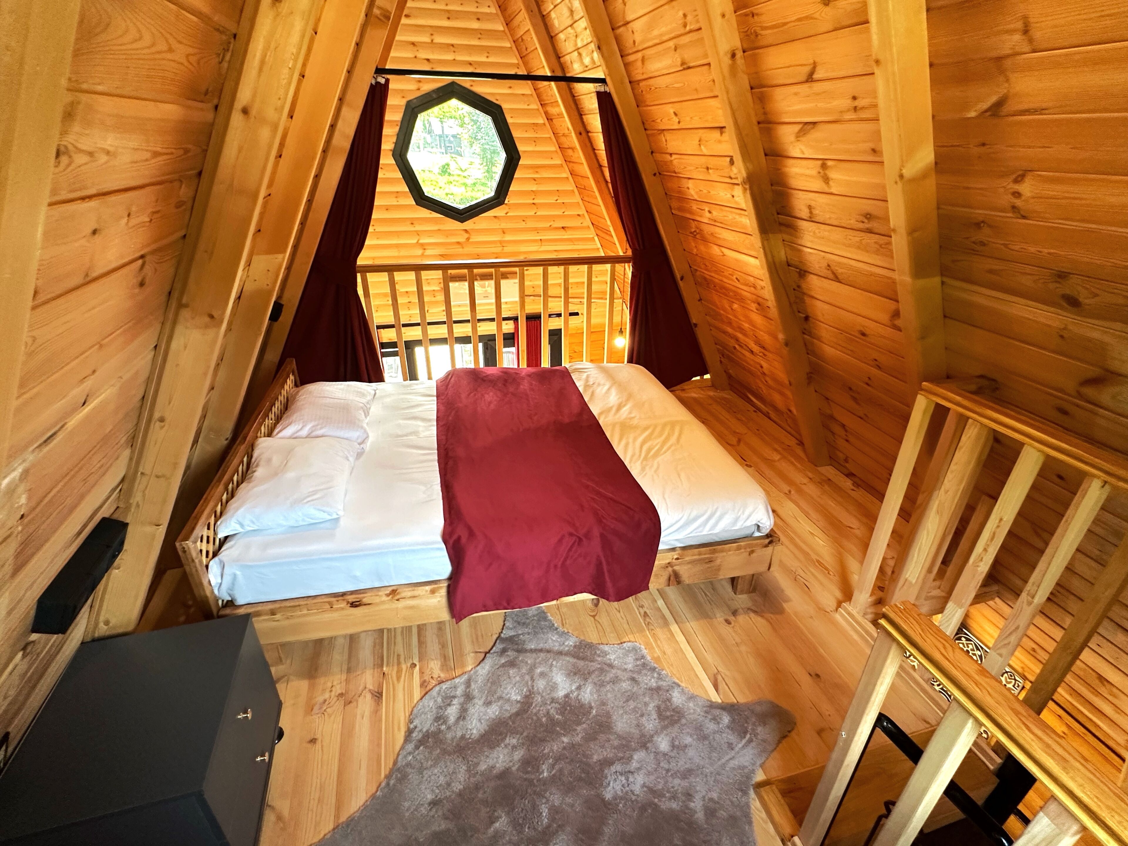 Een gezellige houten kamer met een bed, een raam en een kleine tafel.
