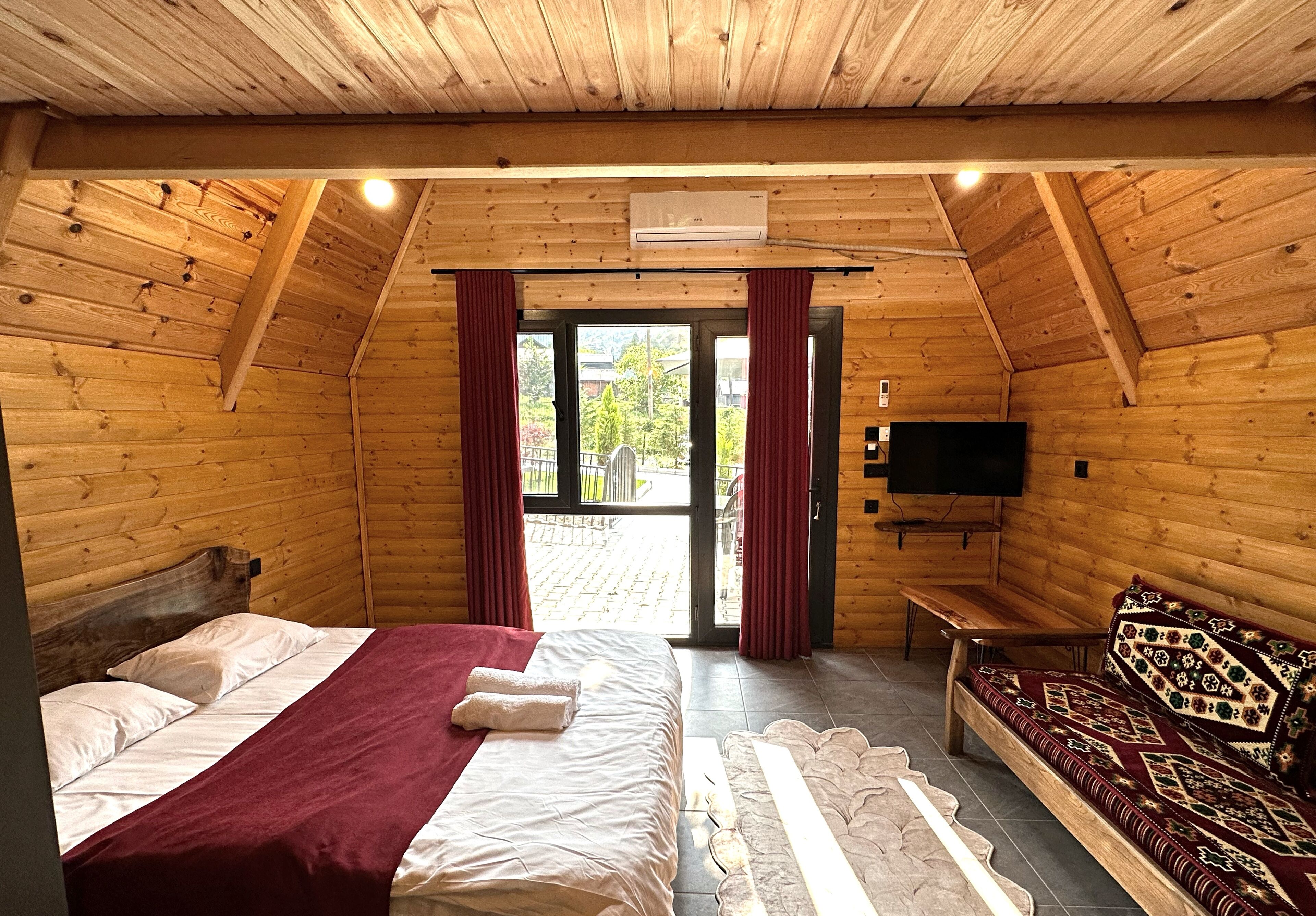 Ein Schlafzimmer einer Holzhütte mit einem Bett, einer Bank, einem Sofa und einem Fernseher.