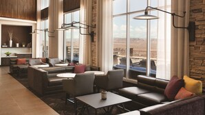 A spacious lounge area with leather sofas, a coffee table, and a view of the desert through large windows. - Hyatt Place Page Lake Powell (Page)