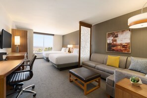 A hotel room with a bed, a sofa, a desk with a chair, a television, and a large window. - Hyatt Place Page Lake Powell (Page)